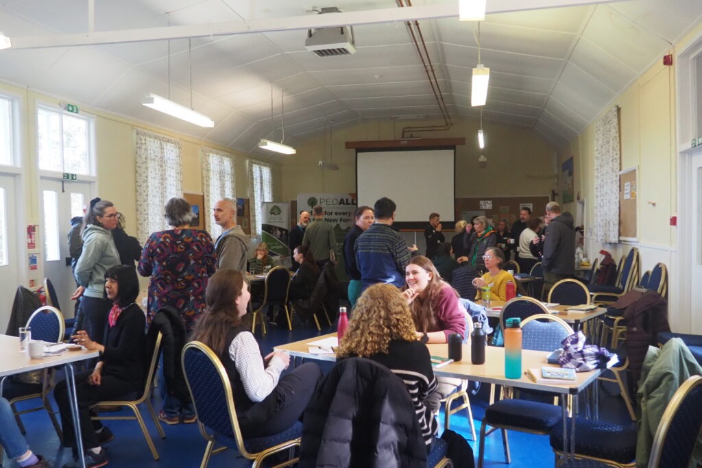 A room full of people talking - some sitting and some standing - during the Green Health Hub's Connect and Learn event.
