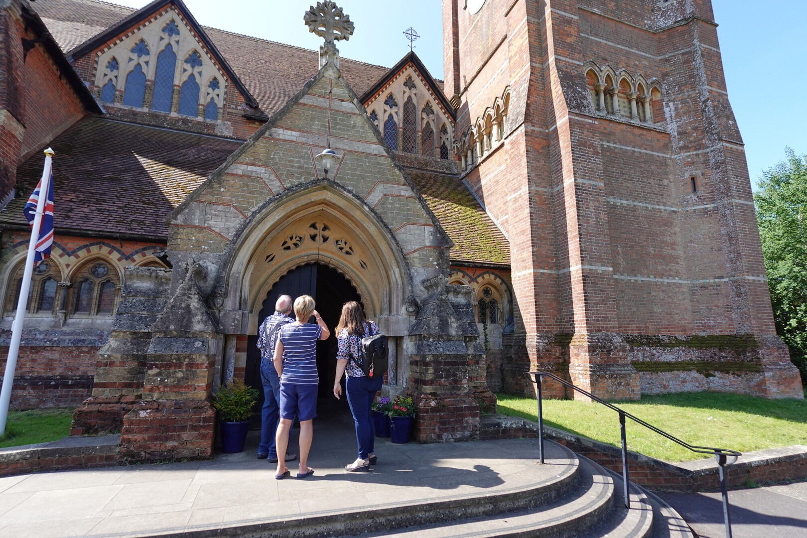 Three people stand outside a church looking up at the spire.