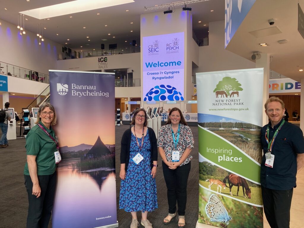 Four people stand at a medical conference event in a foyer with national park banners between them.