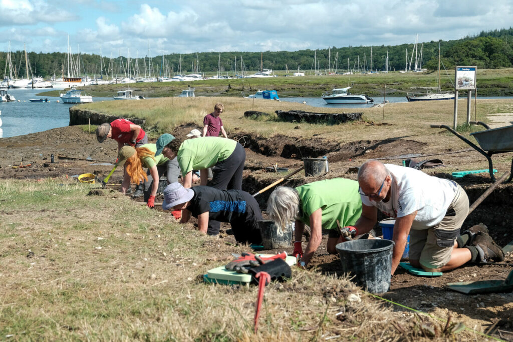 New Forest NPA volunteers kneel on teh ground during an archaeological excavation at Buckler's Hard.